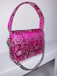 a pink and silver purse with a chain on it