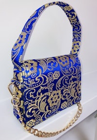a blue and gold handbag with a gold chain